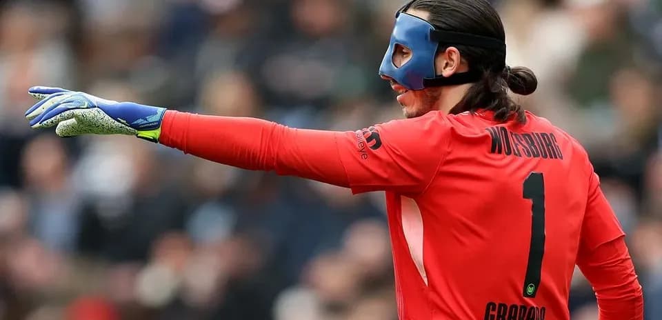Goalkeeper in red jersey directing teammates during match