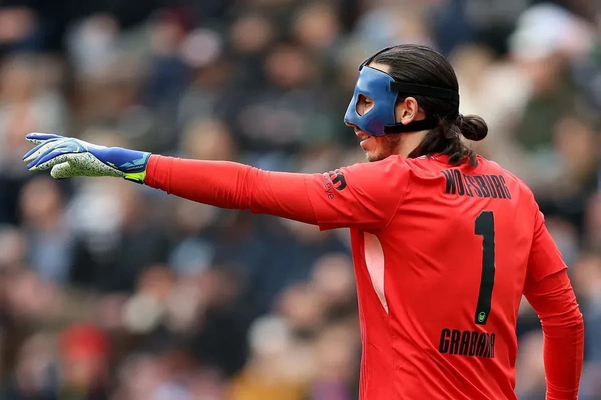 Goalkeeper in red jersey directing teammates during match