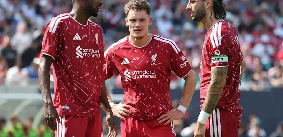 Three Liverpool players discussing on the pitch