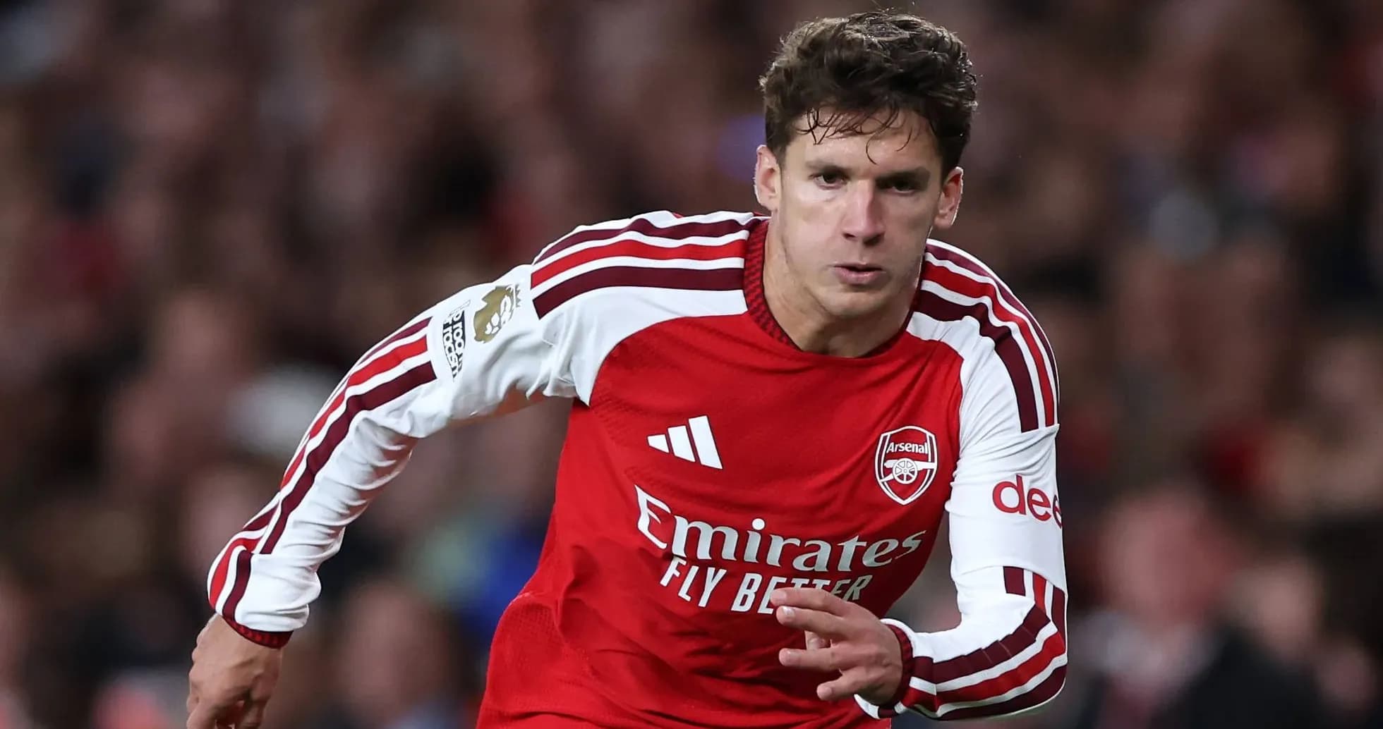 Player sprinting in Arsenal home kit during match