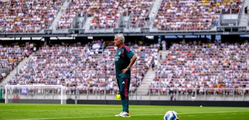 Coach observing match with large crowd in background