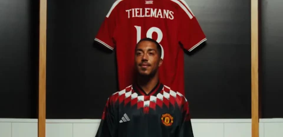 Player posing in front of team jerseys
