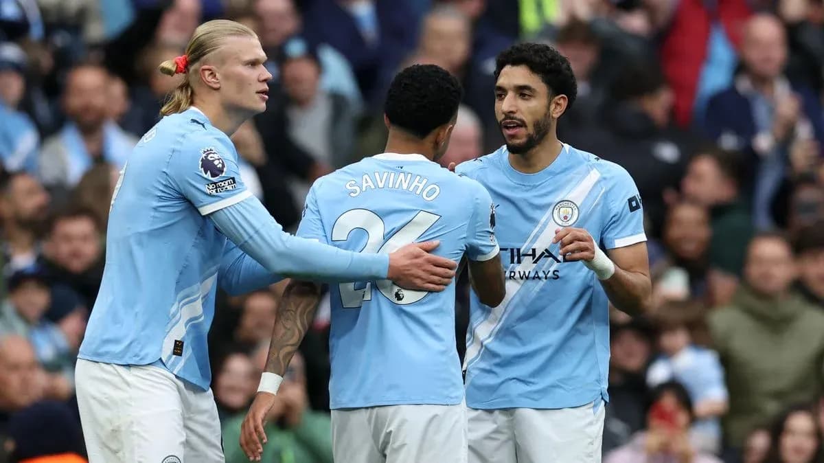Three Manchester City players discussing on the pitch
