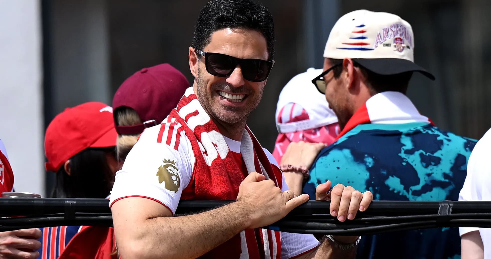 Man in Arsenal shirt and sunglasses smiling in crowd