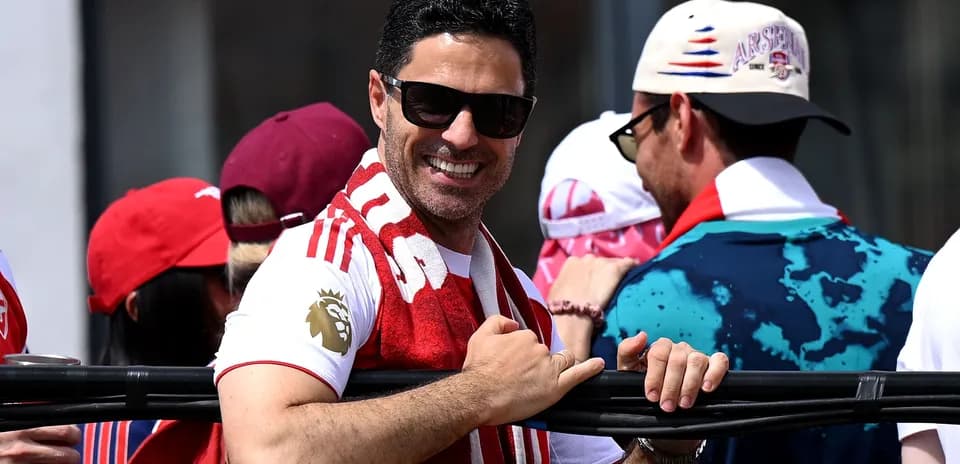 Man in Arsenal shirt and sunglasses smiling in crowd