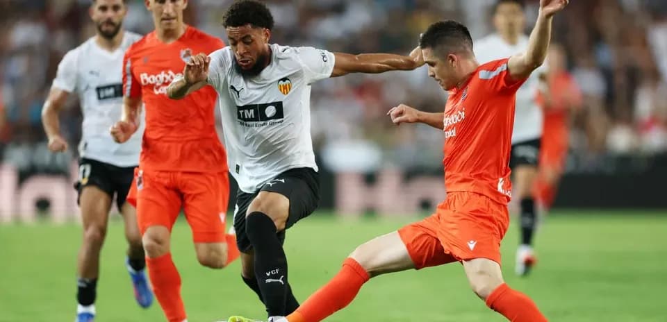 Real Sociedad players challenging Valencia attacker