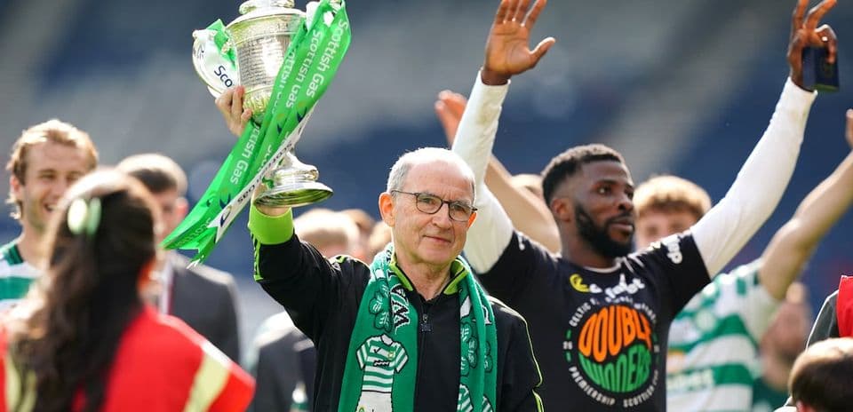 Man holding trophy with Celtic players celebrating