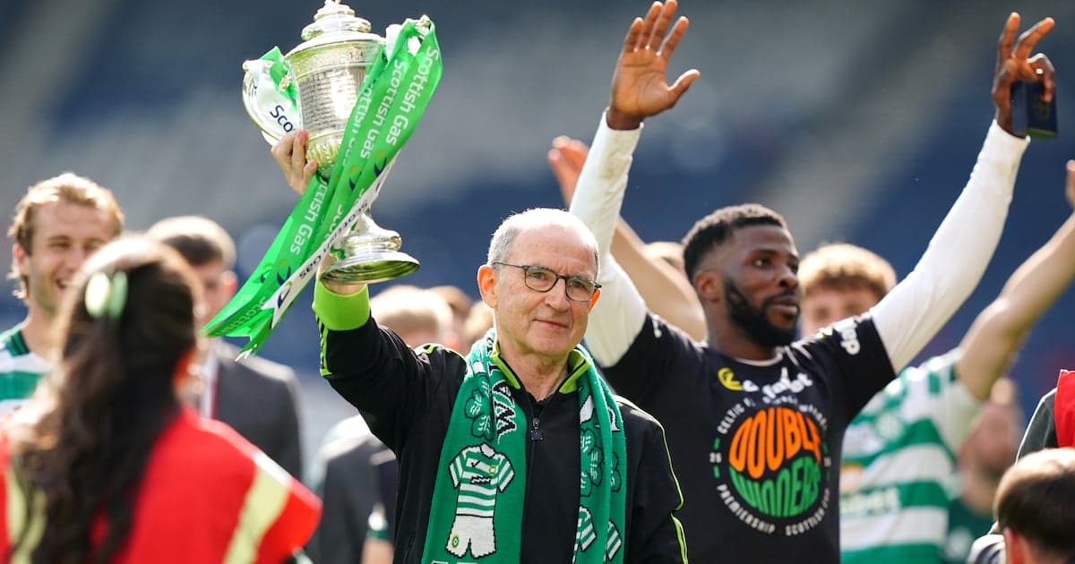 Man holding trophy with Celtic players celebrating