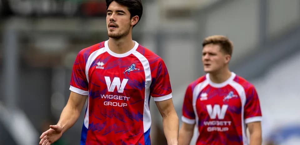 Players in red and blue kits walking on pitch