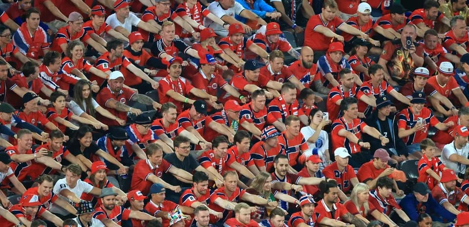 Crowd of fans in red jerseys cheering at event
