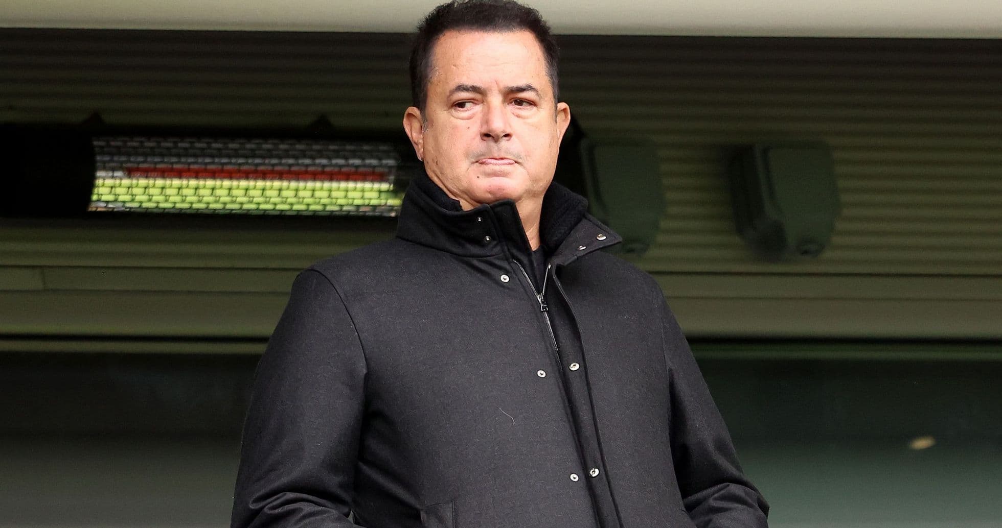 Man in a black coat standing in a stadium