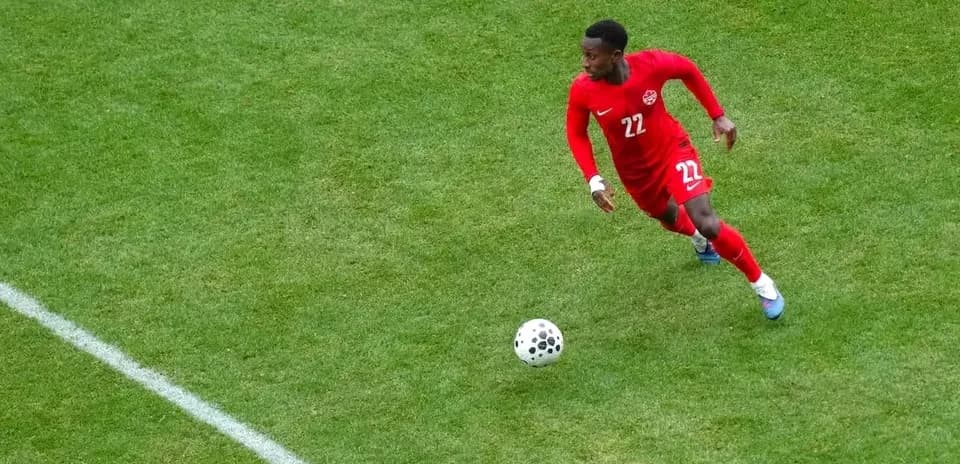 Player in red jersey dribbling ball on field
