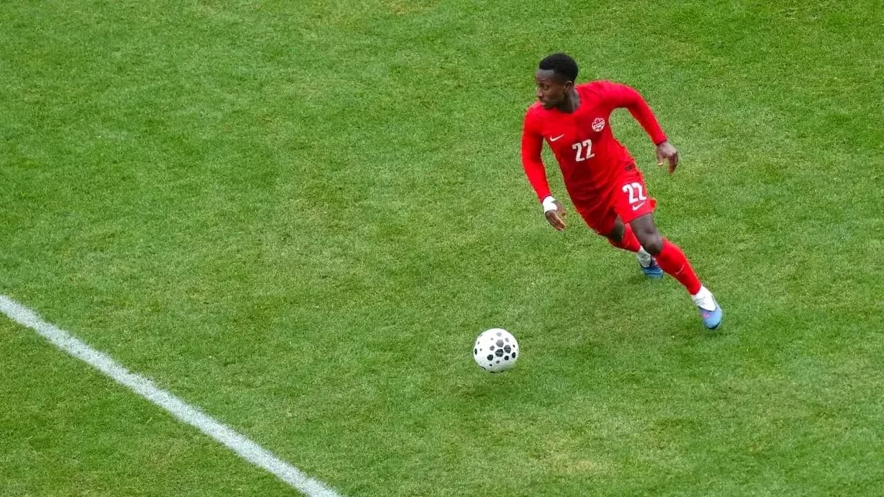 Player in red jersey dribbling ball on field