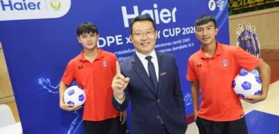 Two young players holding soccer balls with event host