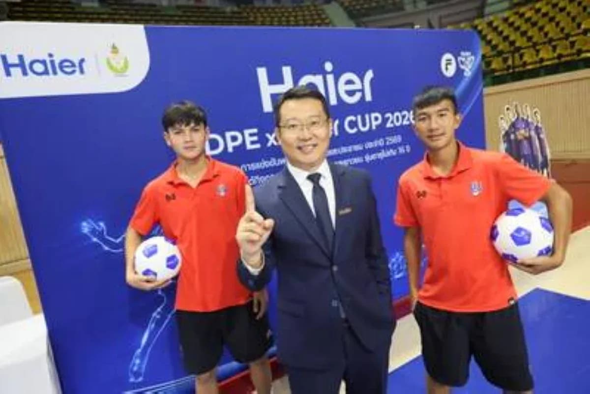 Two young players holding soccer balls with event host