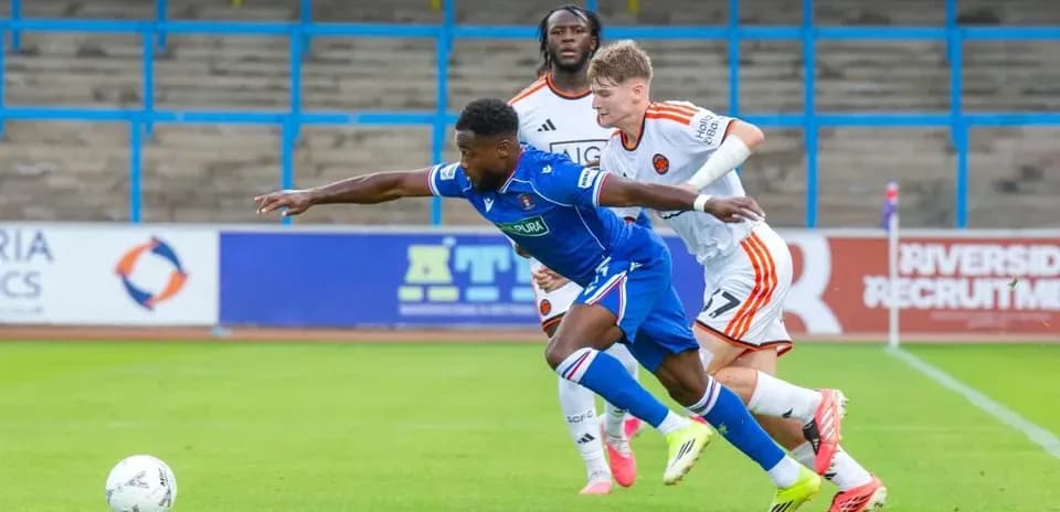 Player in blue shirt stretching for the ball