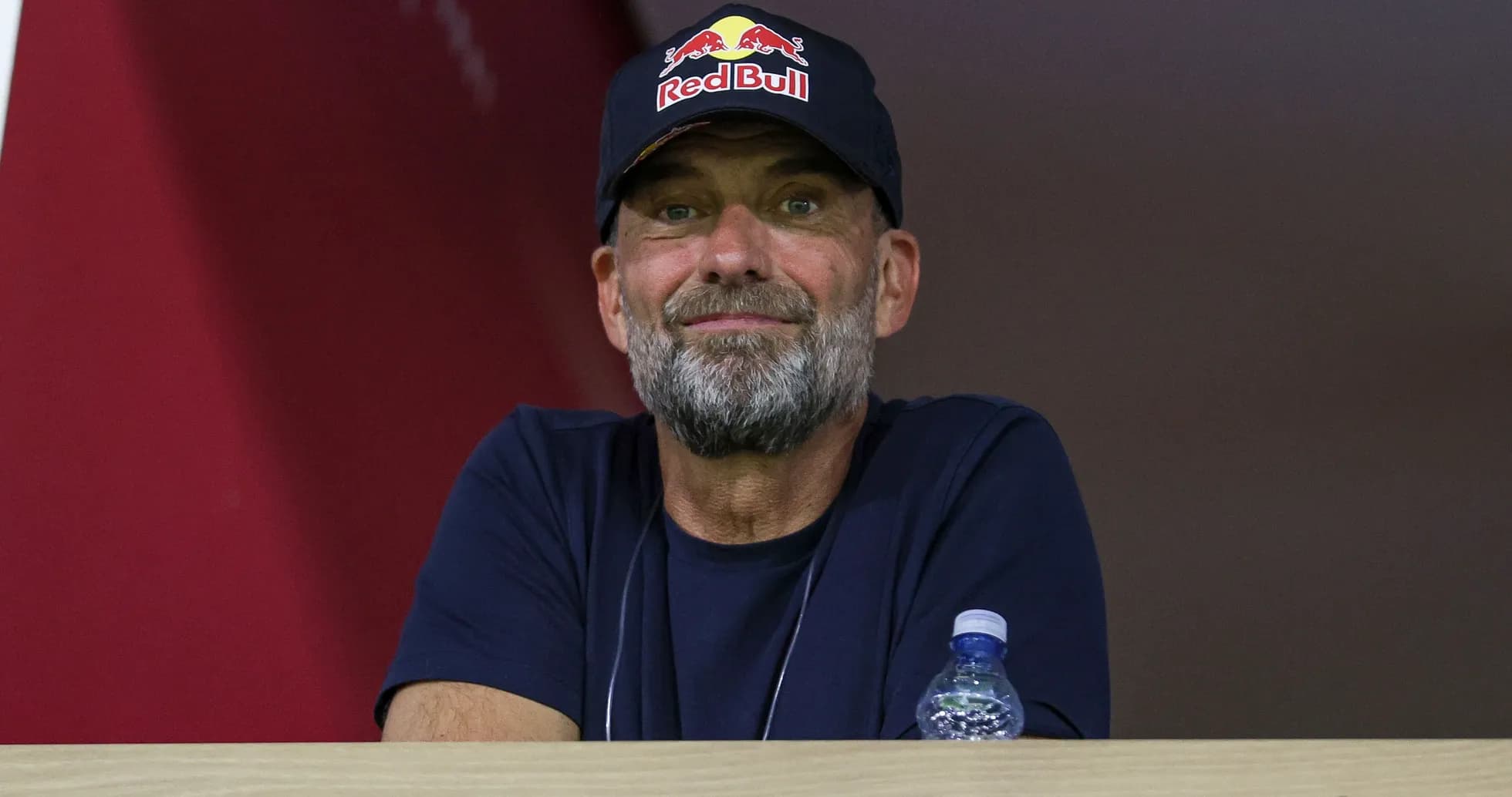 Man in a Red Bull cap observing from a balcony