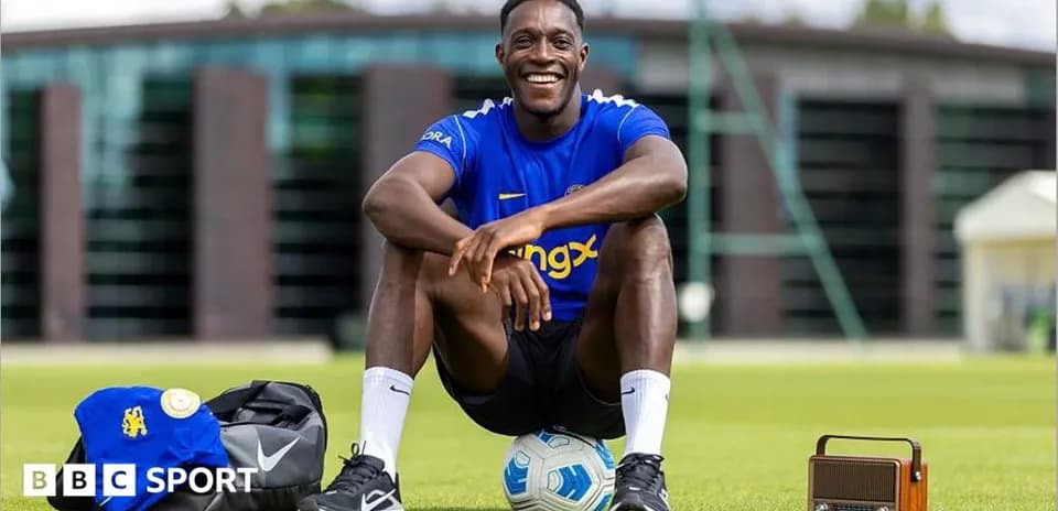 Player sitting on grass with soccer ball and bag