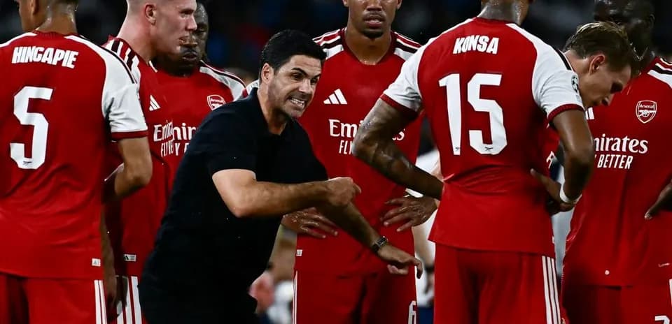 Arsenal players gathered around coach during strategy discussion
