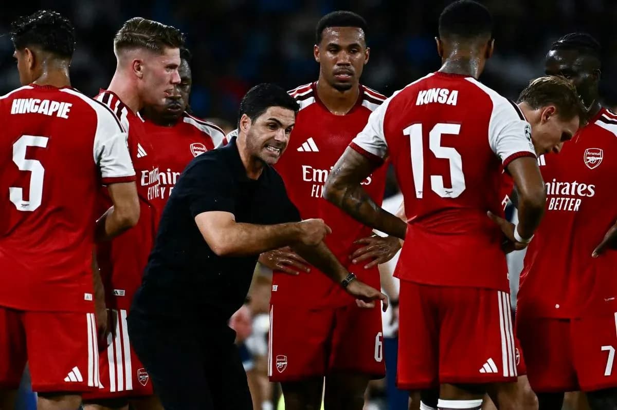 Arsenal players gathered around coach during strategy discussion