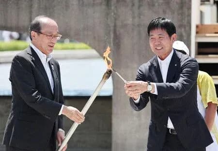 Two officials passing a torch during ceremony