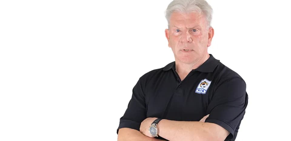 Coach with arms crossed in black polo shirt