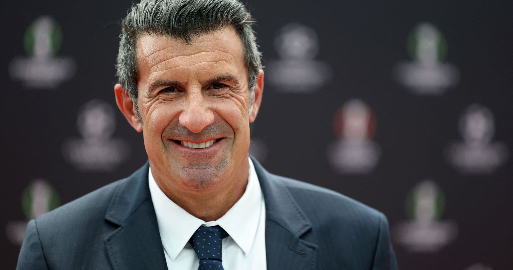 Man smiling in suit at event backdrop