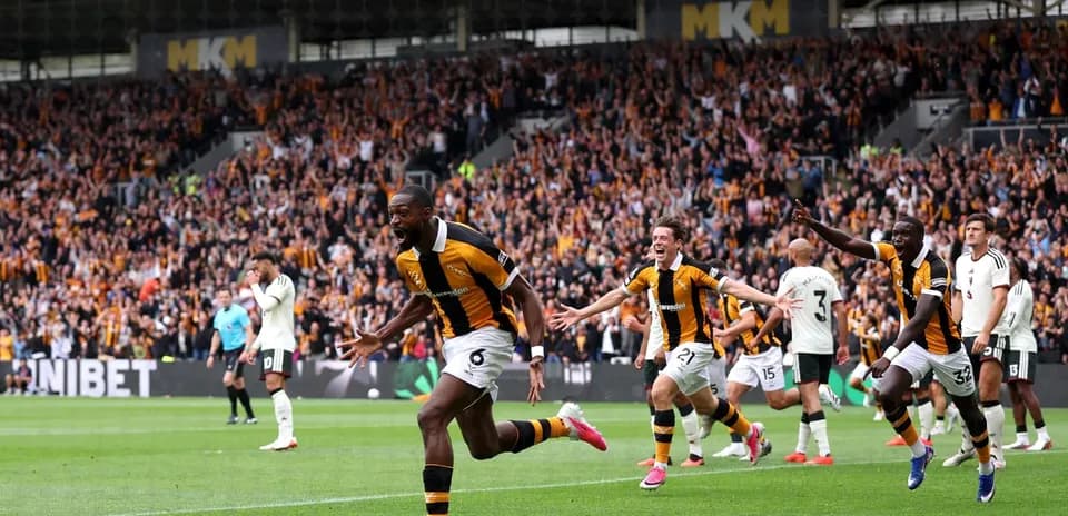Player celebrating a goal with teammates in stadium