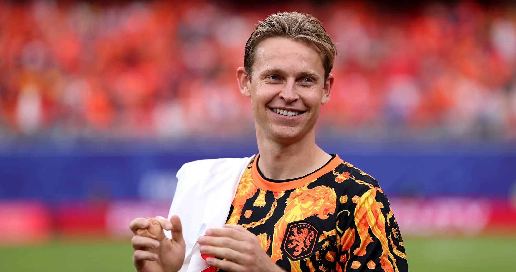 Player smiling in vibrant team-themed outfit on pitch