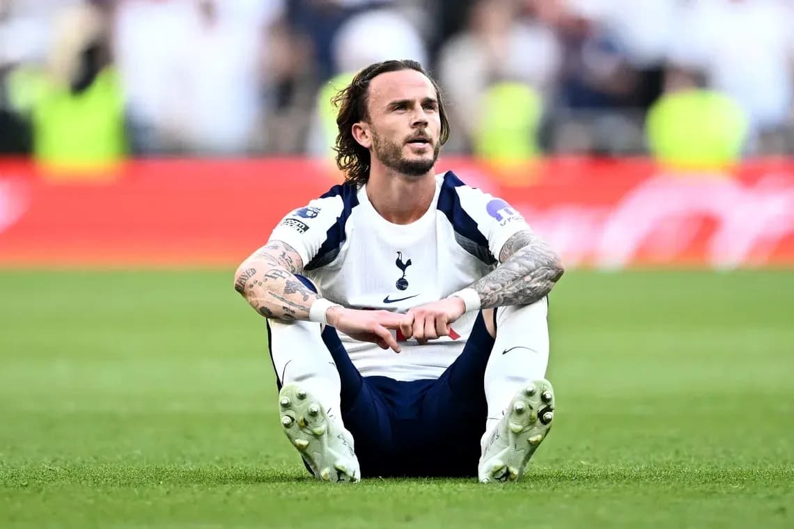 Player sitting on pitch after match wearing Tottenham kit