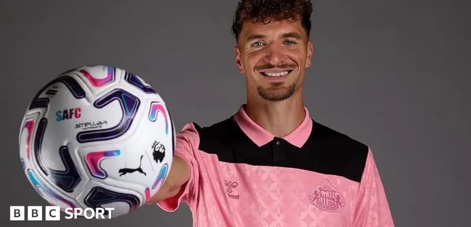 Player holding a football and smiling for camera