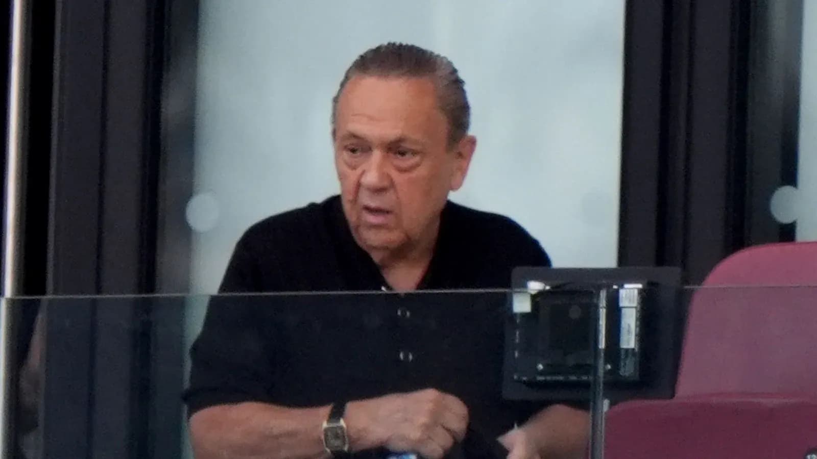 Man observing from a glass-enclosed VIP box