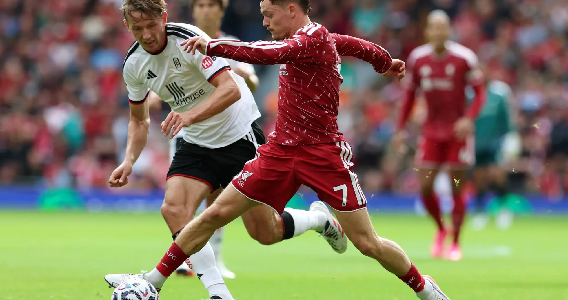 Liverpool player challenging Fulham opponent for the ball