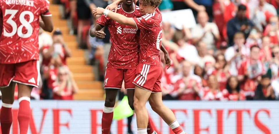Two Liverpool players celebrating a goal on the pitch