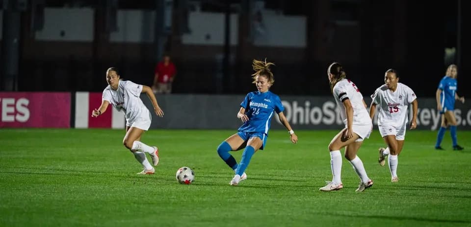Player in blue dribbling past defenders in soccer match