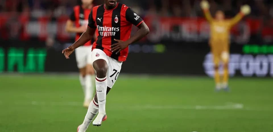 Player in AC Milan kit running with ball
