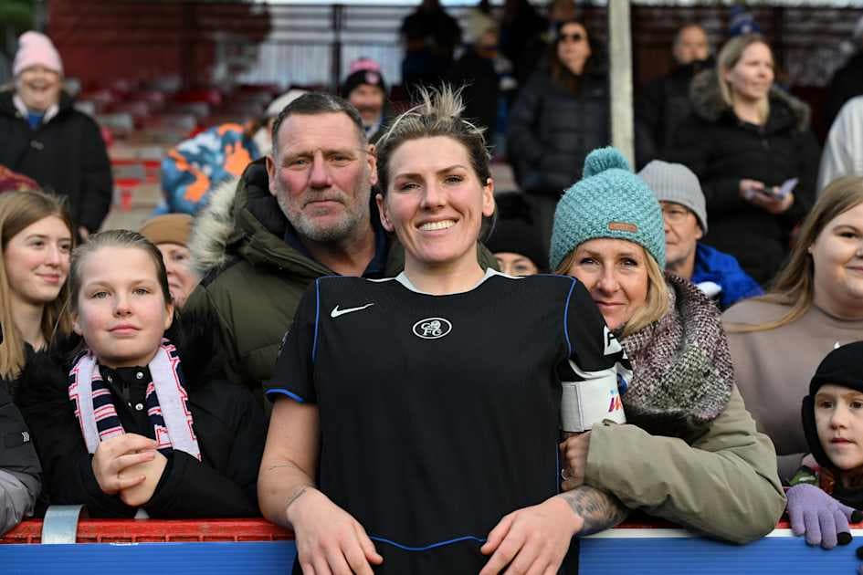 Player smiling with fans at stadium railing