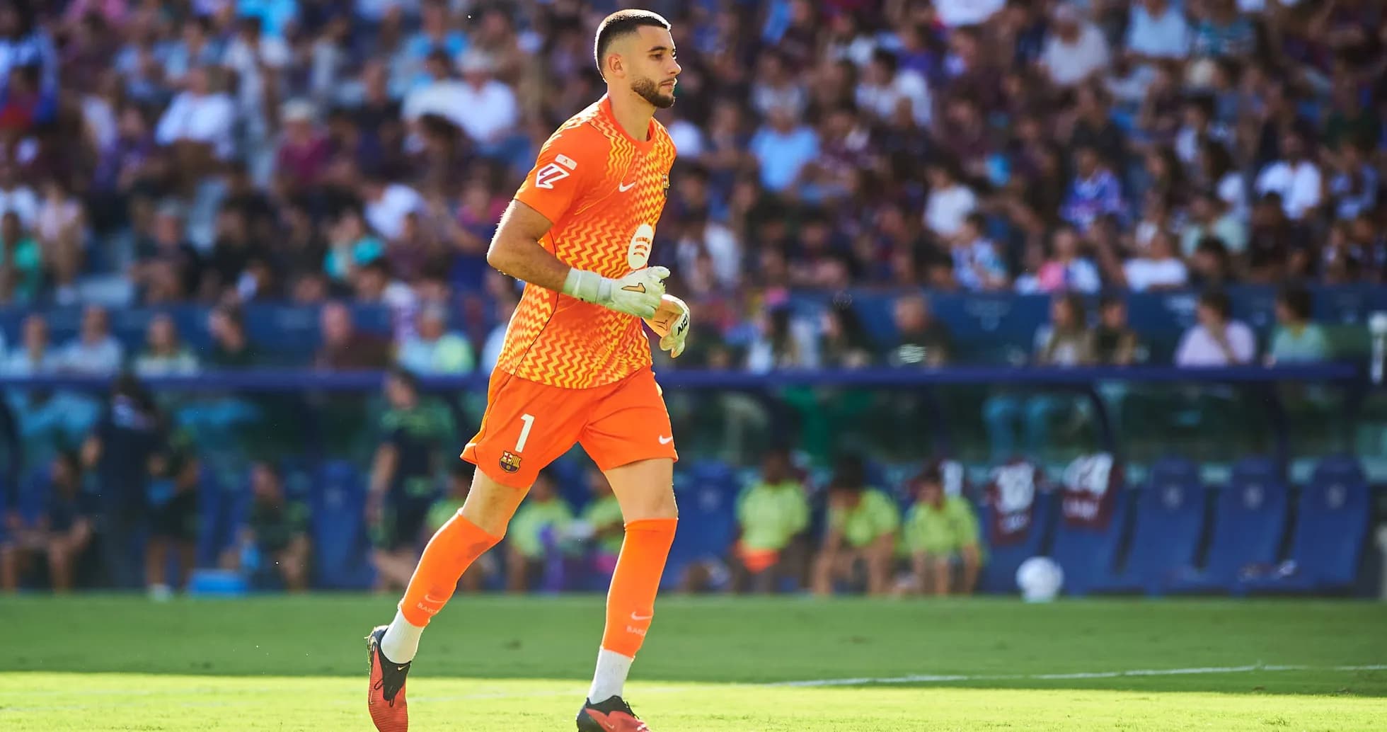 Goalkeeper in orange kit running on the pitch