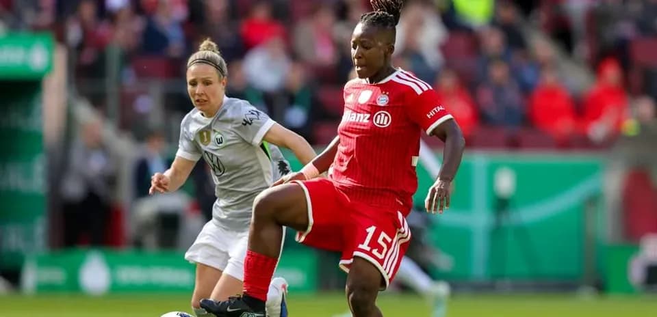 Two female football players competing for the ball
