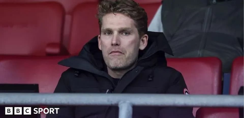 Person seated in stadium wearing a black coat
