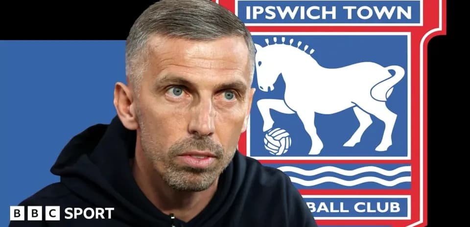 Coach speaking with Ipswich Town logo in background