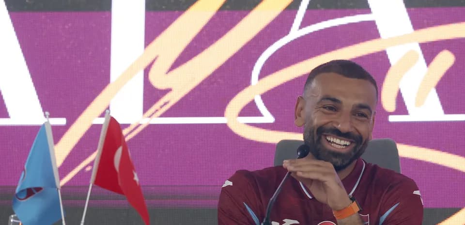 Player smiling during press conference with flags