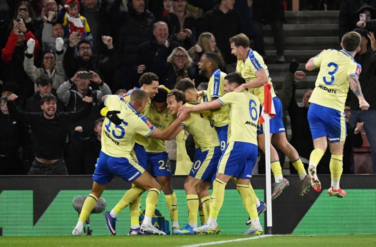 Players celebrating a goal with fans in background