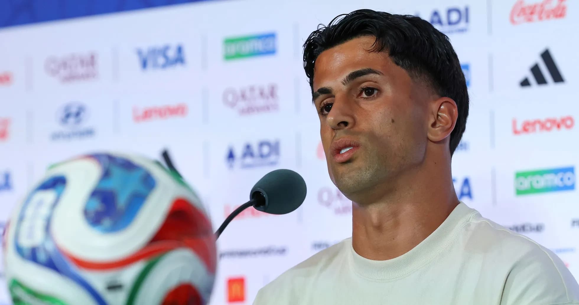 Player speaking at press conference with ball in foreground
