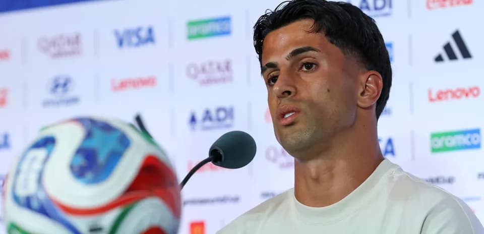 Player speaking at press conference with ball in foreground