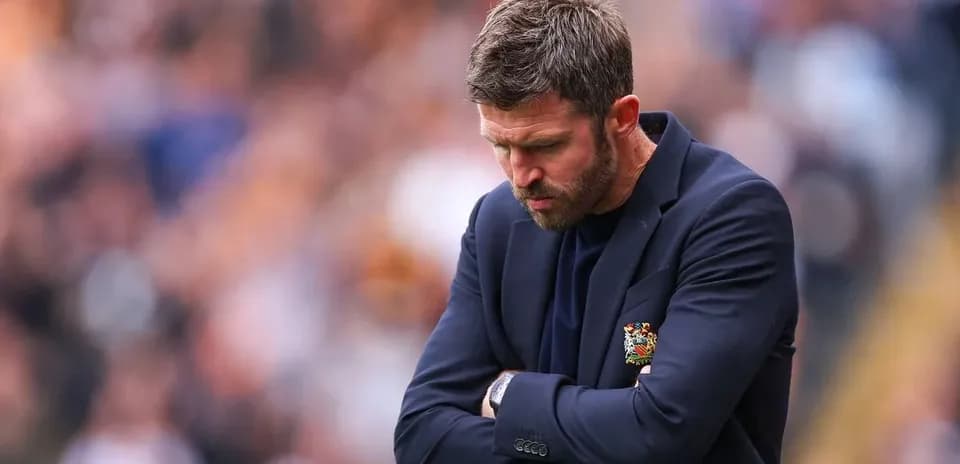 Coach with arms crossed, looking down during match