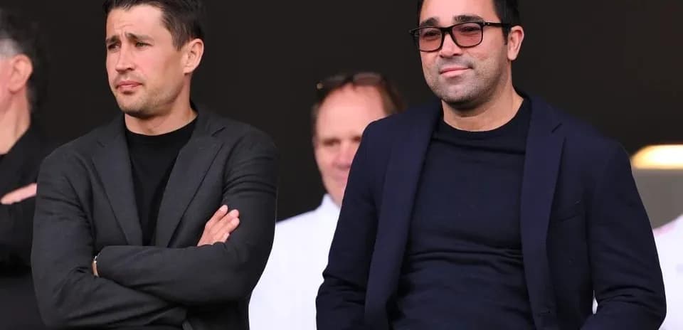 Two men in suits watching an event