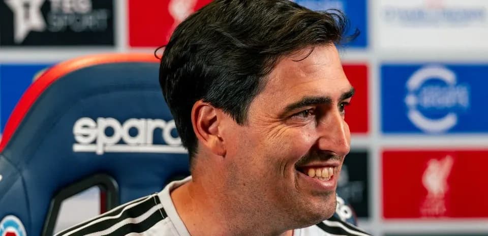 Coach smiling during press conference at podium