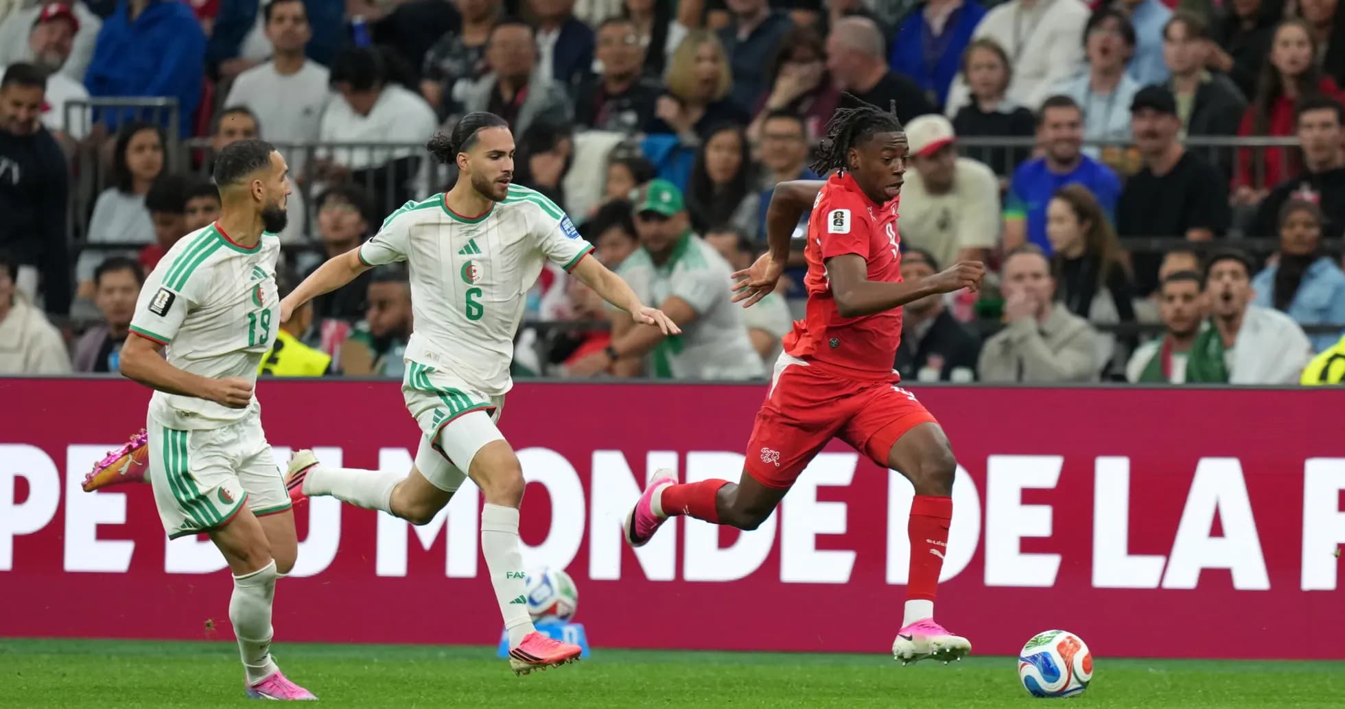 Switzerland player dribbling past Algeria defenders
