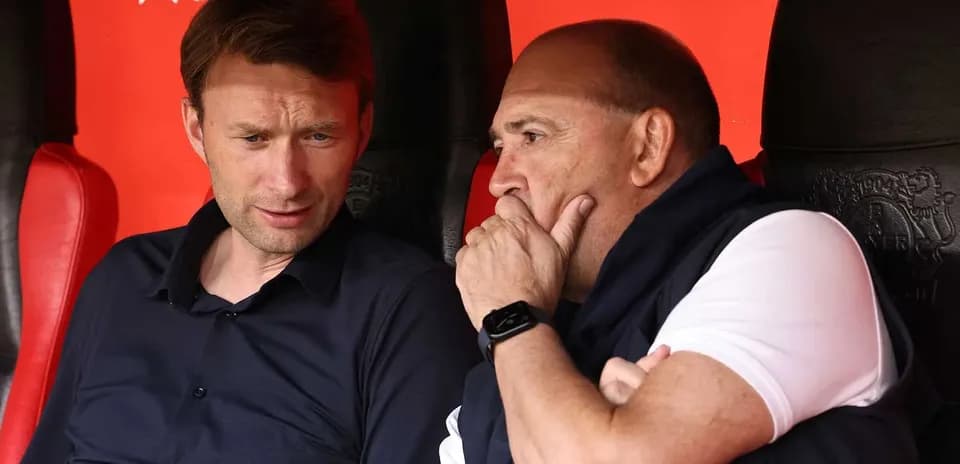 Two coaches discussing strategies on the bench